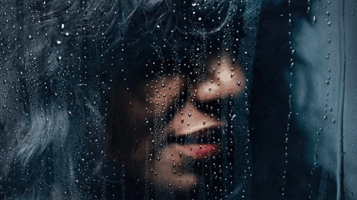 Primal Scream featured vocalist Denise Johnson behind a window pane covered in water droplets.