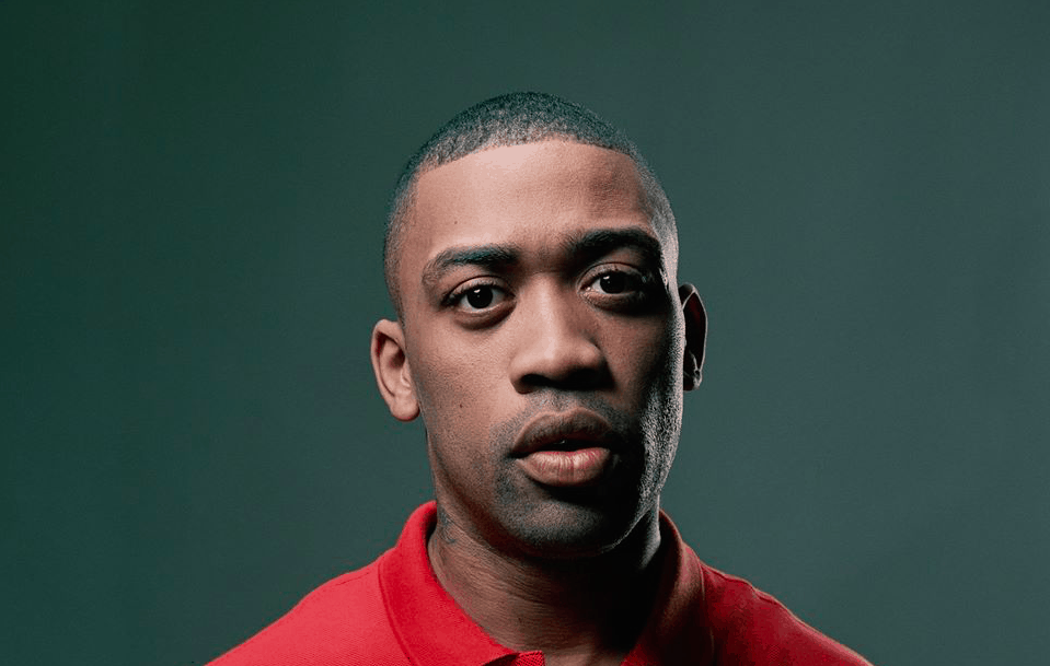 Color photo of U.K. Grime rapper Wiley wearing a red polo shirt.