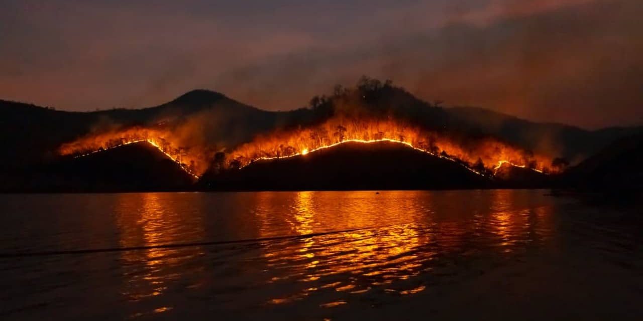 A photo of a wildfire near a lake, beach or other body of water taken by Sippakorn Yamkasikorn.