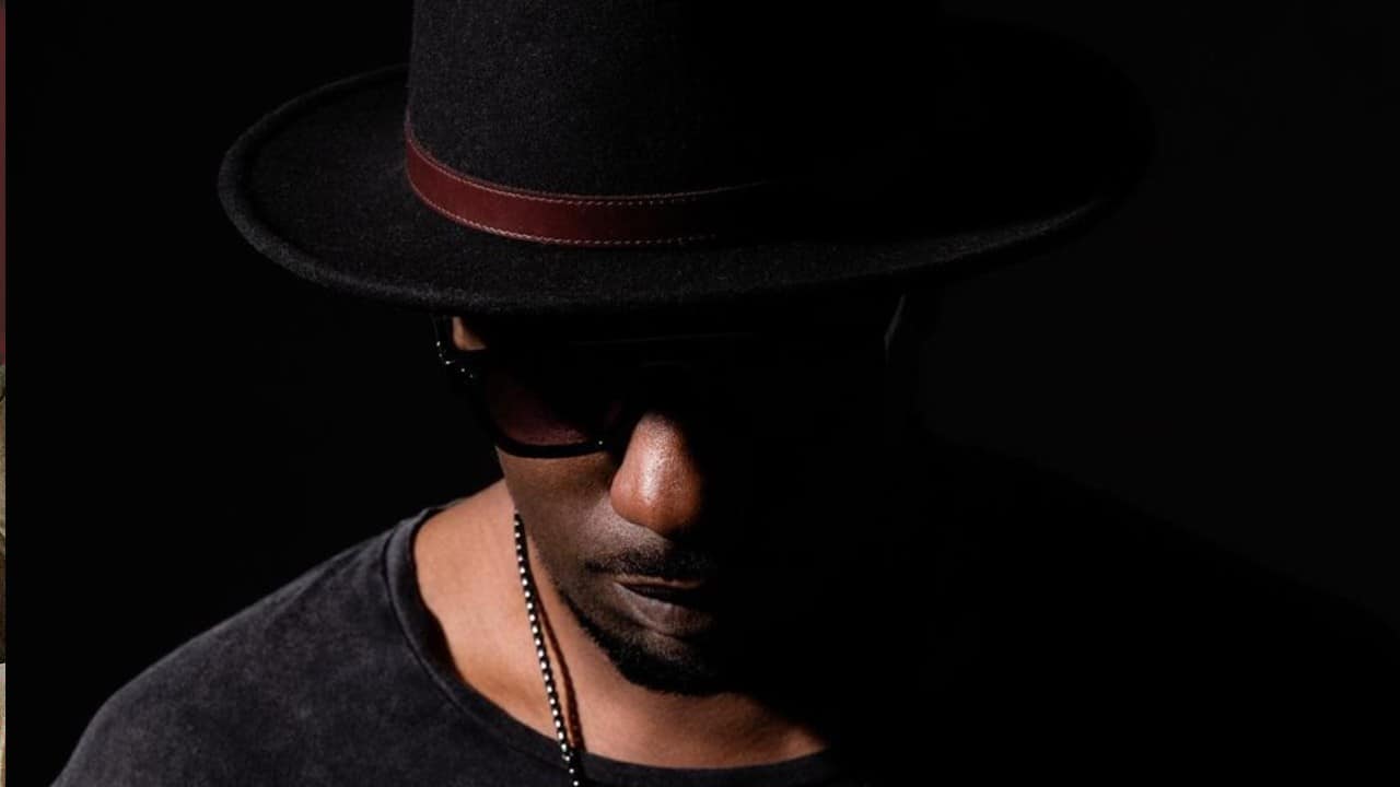 Color press photo of Chicago DJ and producer Gene Farris wearing a hat in front of a black background.