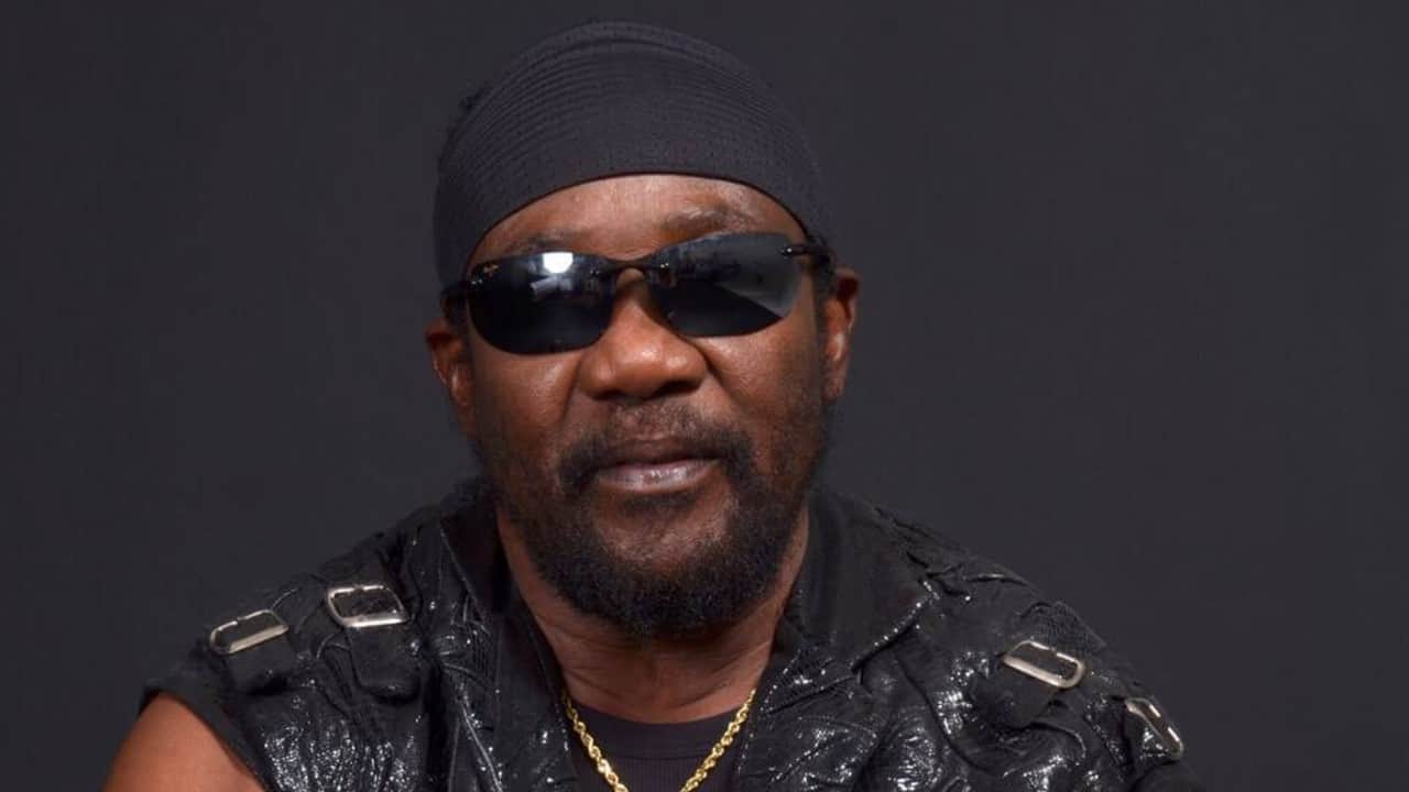 Toots Hibbert of Toots and the Maytals wearing a black leather vest, do rag and sunglasses.