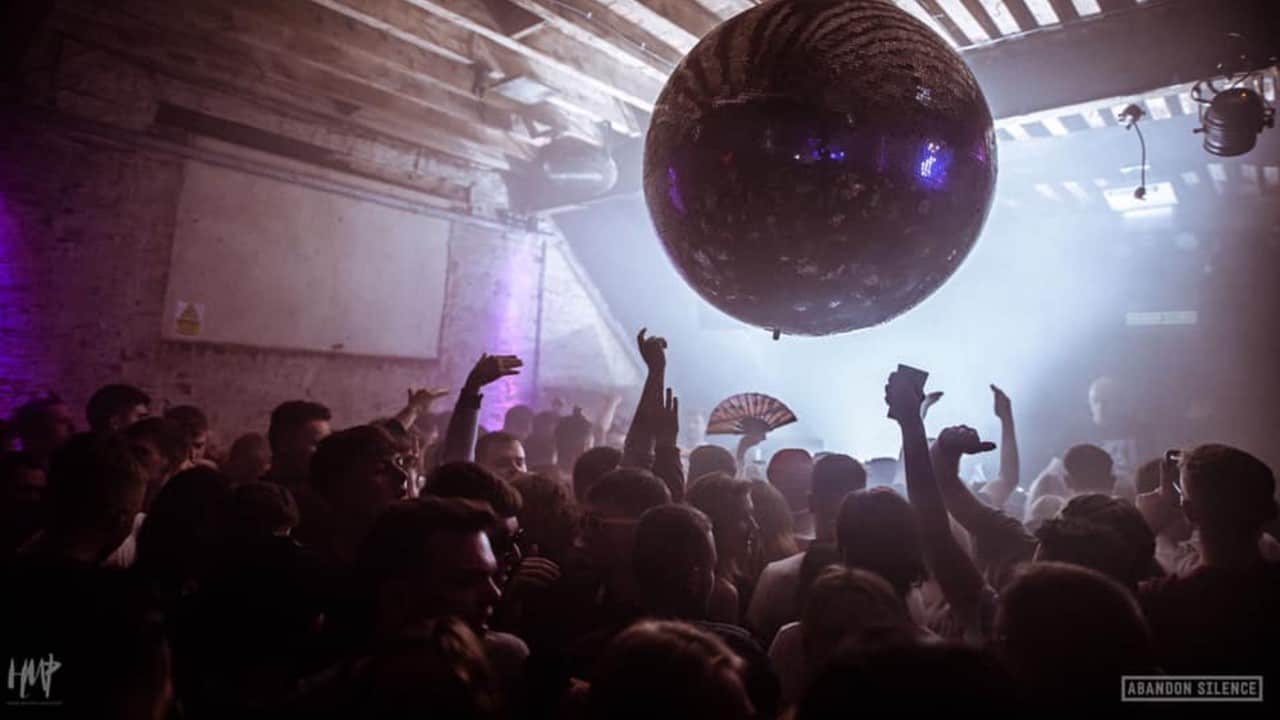 A crowd dancing under a large disco ball at 24 Kitchen Street in Liverpool.