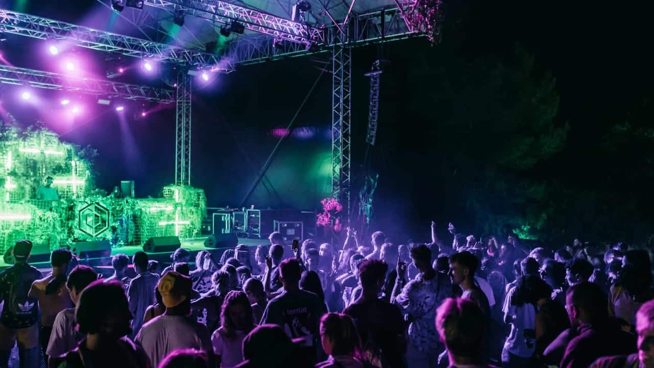 A crowd dancing in front of a stage at Dimensions Festival.